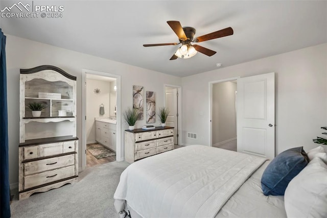 bedroom with ceiling fan, light colored carpet, and connected bathroom