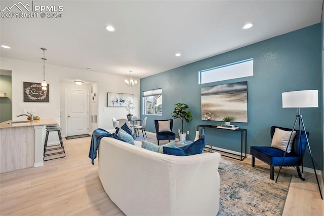 living room featuring sink, light wood-type flooring, and a notable chandelier