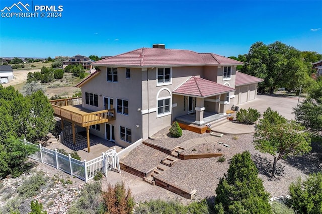 back of property with a gate, fence, concrete driveway, a garage, and a tiled roof