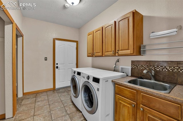 washroom featuring light tile patterned floors, sink, separate washer and dryer, cabinets, and a textured ceiling