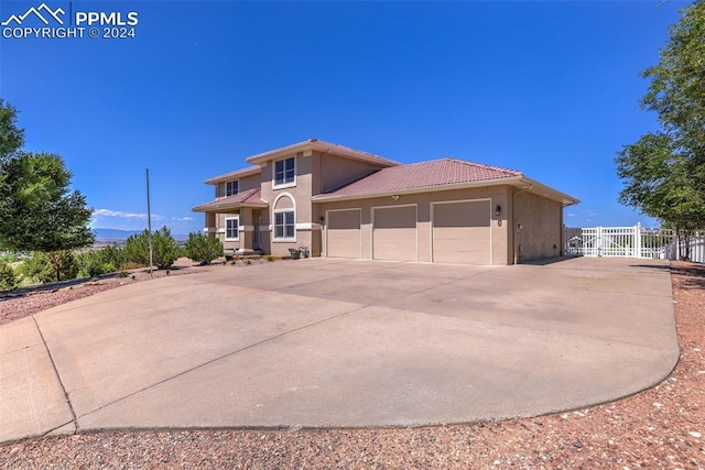 view of front of house featuring fence, a tile roof, concrete driveway, stucco siding, and an attached garage