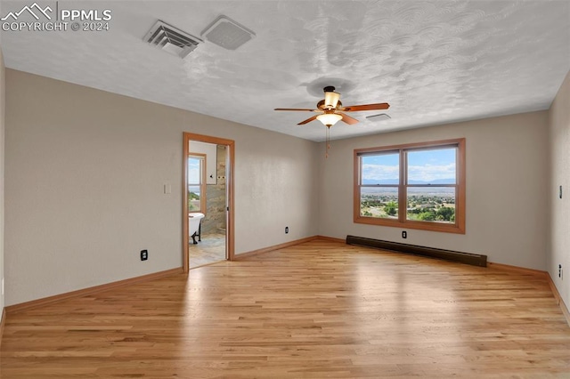 unfurnished room featuring a baseboard heating unit, ceiling fan, a textured ceiling, and light hardwood / wood-style flooring