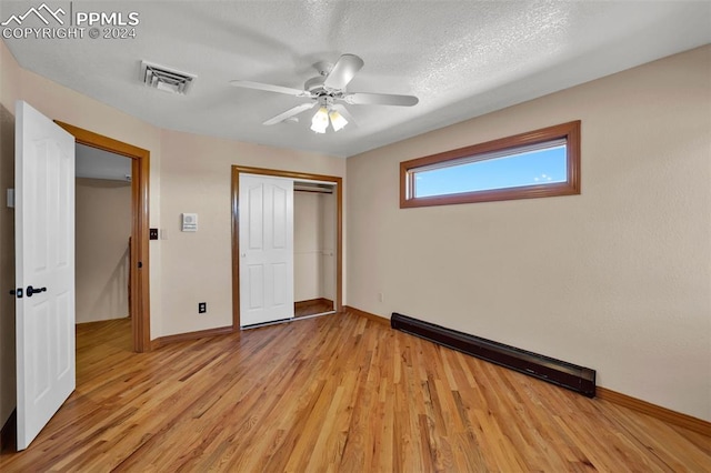 unfurnished bedroom with a textured ceiling, light hardwood / wood-style flooring, ceiling fan, and a closet