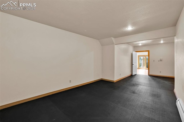 carpeted empty room featuring a textured ceiling and a baseboard radiator