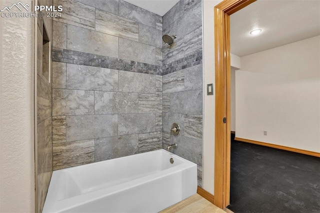 bathroom with tiled shower / bath combo and a textured ceiling