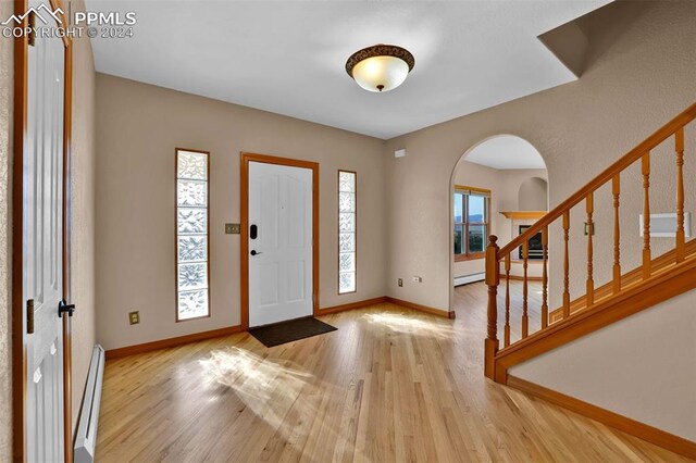 entryway with light wood-type flooring, crown molding, a baseboard heating unit, and ceiling fan