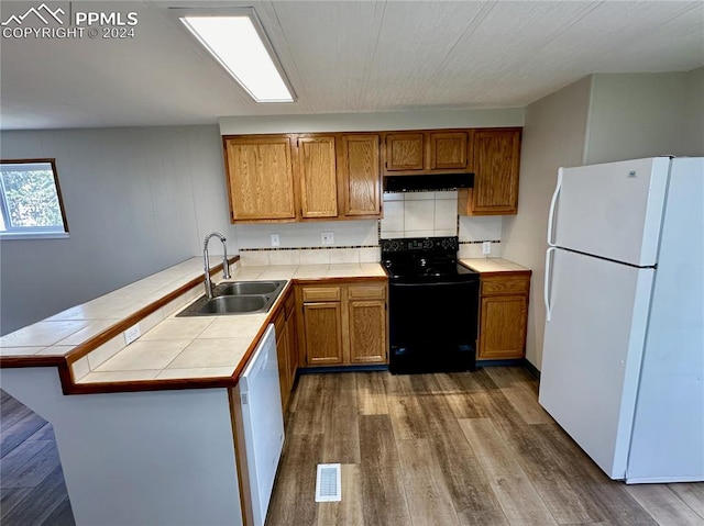 kitchen with kitchen peninsula, sink, tile countertops, and white appliances