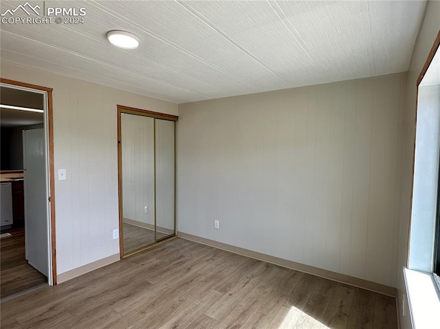 unfurnished bedroom with light hardwood / wood-style flooring and a closet