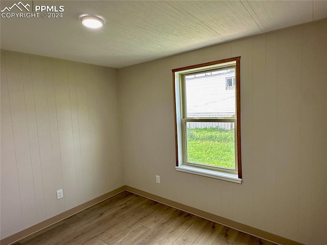 empty room with light hardwood / wood-style flooring and wood walls