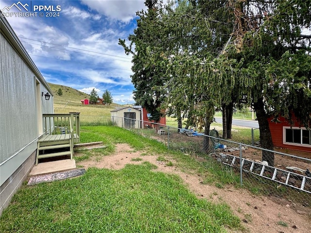 view of yard featuring a wooden deck and a storage unit