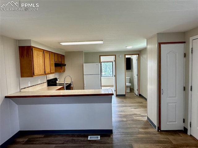 kitchen featuring white refrigerator, kitchen peninsula, black electric range oven, dark wood-type flooring, and tile counters