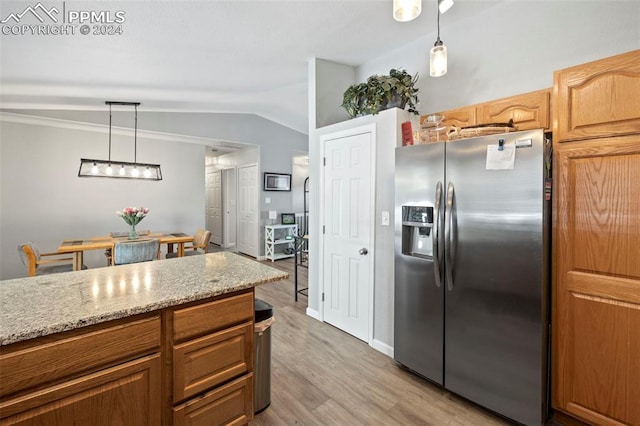 kitchen featuring light hardwood / wood-style flooring, decorative light fixtures, light stone counters, lofted ceiling, and stainless steel fridge