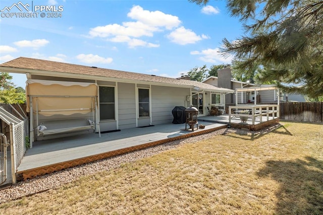 rear view of property with a lawn and a deck