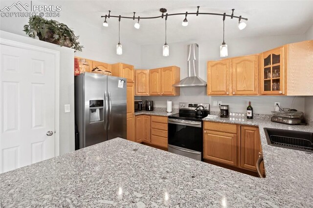 kitchen featuring pendant lighting, appliances with stainless steel finishes, sink, light stone counters, and wall chimney range hood