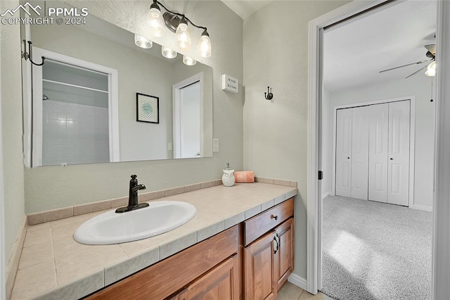 bathroom with a shower, ceiling fan, and vanity