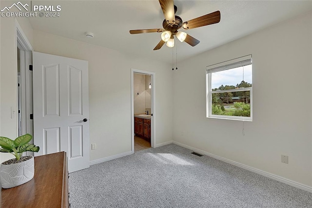 unfurnished bedroom featuring light carpet, ensuite bathroom, and ceiling fan