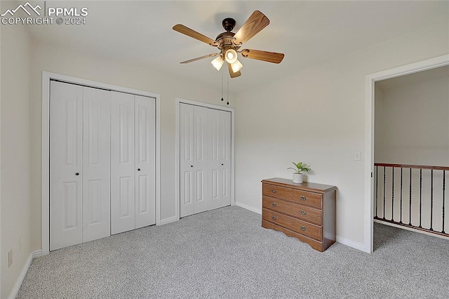 bedroom featuring two closets, light colored carpet, and ceiling fan