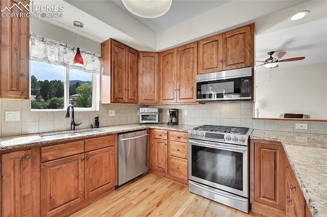 kitchen with light hardwood / wood-style flooring, decorative light fixtures, stainless steel appliances, sink, and ceiling fan