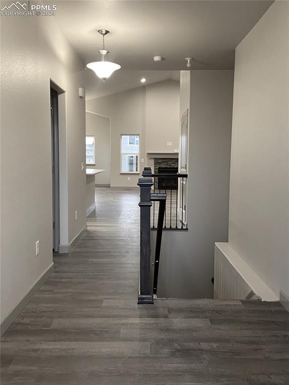 hallway featuring dark wood-type flooring and vaulted ceiling