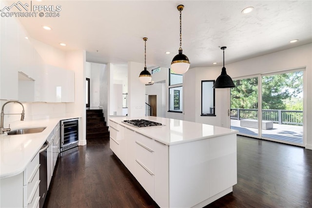 kitchen with beverage cooler, a kitchen island, sink, and decorative light fixtures