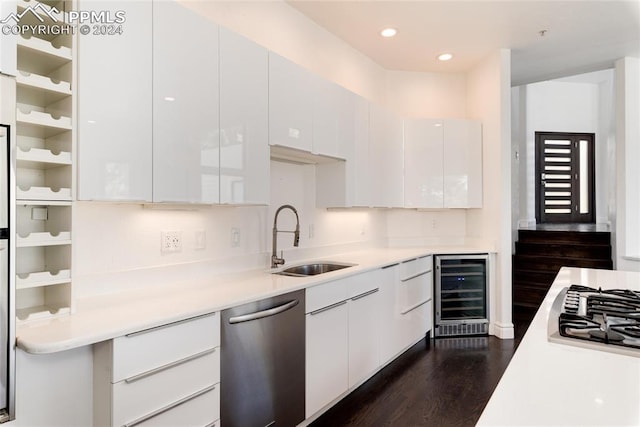 kitchen featuring white cabinets, stainless steel appliances, dark hardwood / wood-style flooring, sink, and beverage cooler