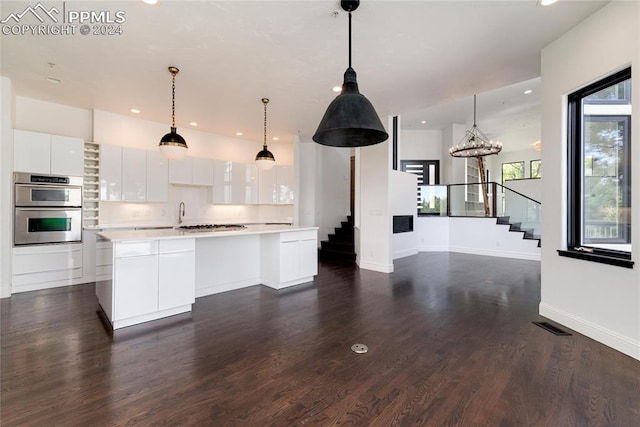 kitchen featuring a kitchen island, dark wood-type flooring, hanging light fixtures, appliances with stainless steel finishes, and white cabinets