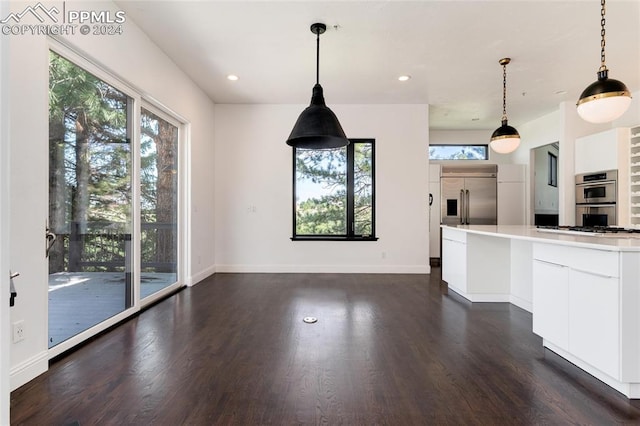 kitchen featuring appliances with stainless steel finishes, decorative light fixtures, white cabinets, and dark hardwood / wood-style floors