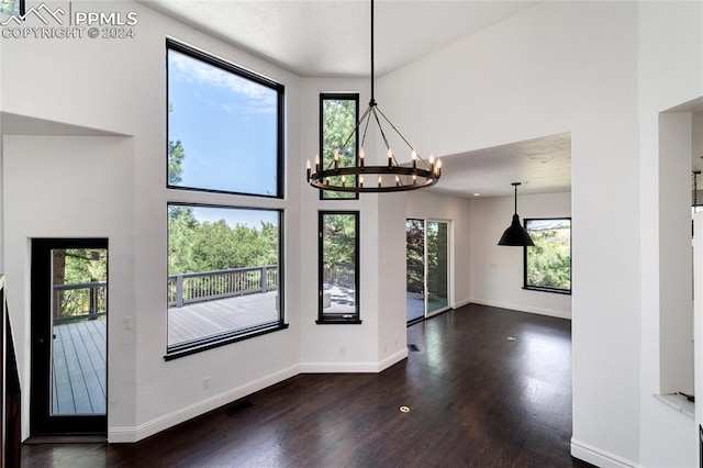 interior space featuring a high ceiling, an inviting chandelier, plenty of natural light, and dark hardwood / wood-style floors