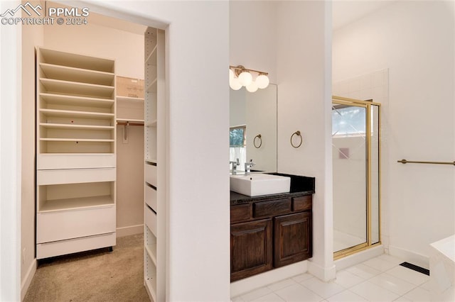 bathroom featuring tile patterned floors, a shower with shower door, and vanity