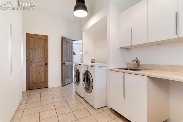 clothes washing area with light tile patterned floors, cabinets, washer and dryer, and sink