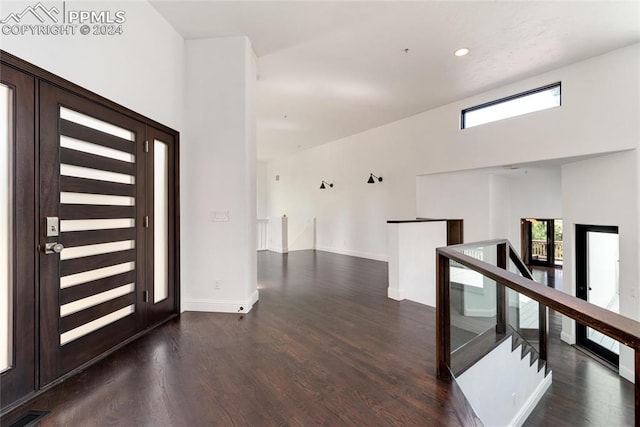 entryway with dark hardwood / wood-style floors and a towering ceiling