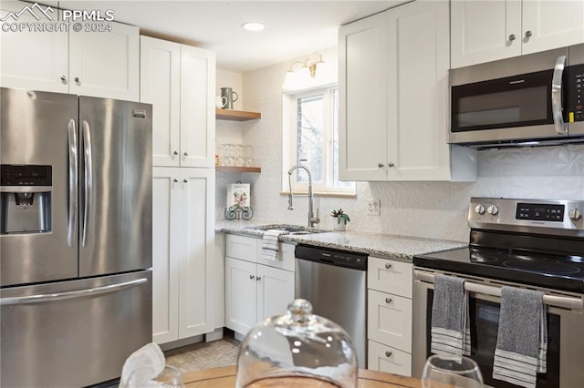 kitchen featuring tasteful backsplash, light stone counters, sink, appliances with stainless steel finishes, and white cabinets