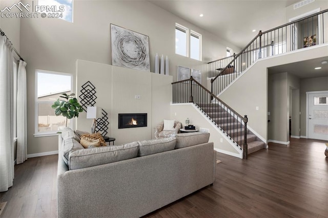 living room featuring a towering ceiling and dark hardwood / wood-style flooring