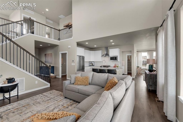 living room with sink, dark hardwood / wood-style flooring, and a towering ceiling