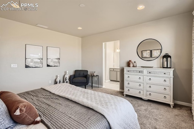 bedroom with ensuite bathroom and light carpet