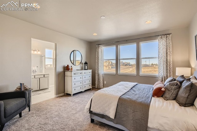 bedroom featuring ensuite bath and light carpet