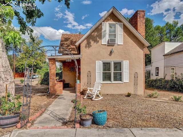 view of front facade featuring a patio area, a chimney, cooling unit, and stucco siding