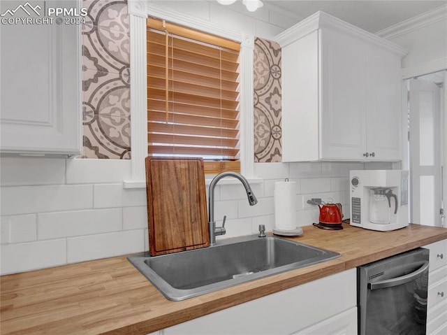 kitchen with ornamental molding, white cabinetry, dishwasher, wooden counters, and sink