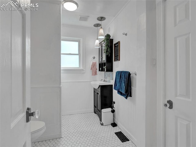 bathroom with tile patterned flooring, vanity, toilet, and crown molding