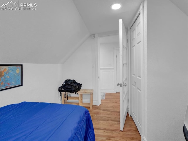 bedroom featuring lofted ceiling, a closet, and light hardwood / wood-style flooring