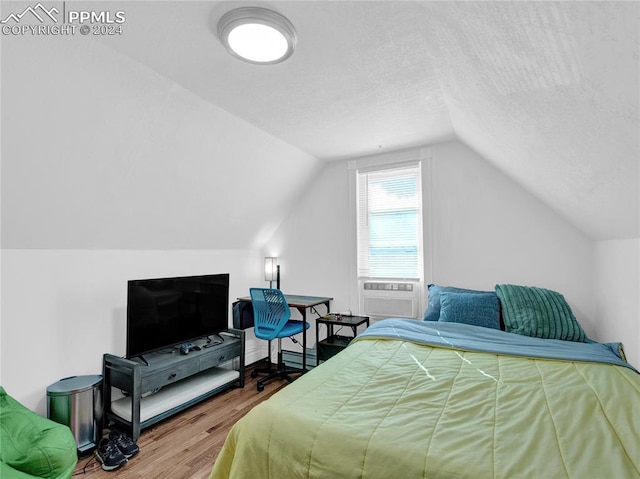 bedroom featuring a textured ceiling, vaulted ceiling, cooling unit, wood-type flooring, and a baseboard heating unit