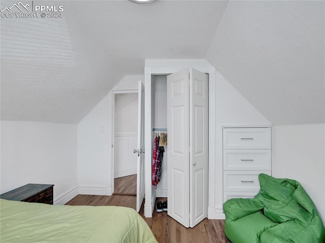 bedroom featuring vaulted ceiling, a closet, and hardwood / wood-style flooring