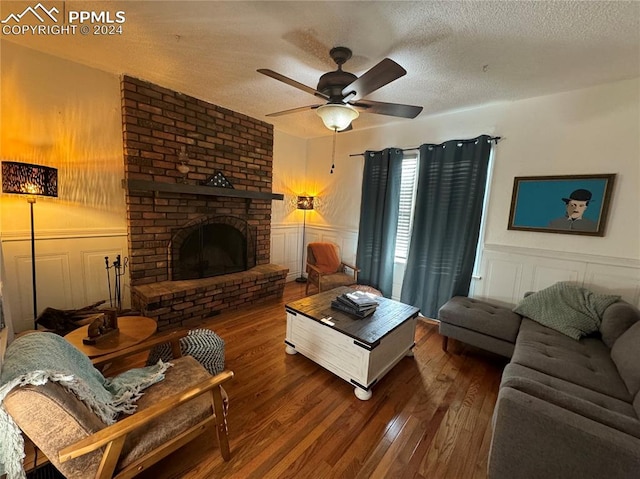 living room featuring a fireplace, a textured ceiling, wood-type flooring, and ceiling fan