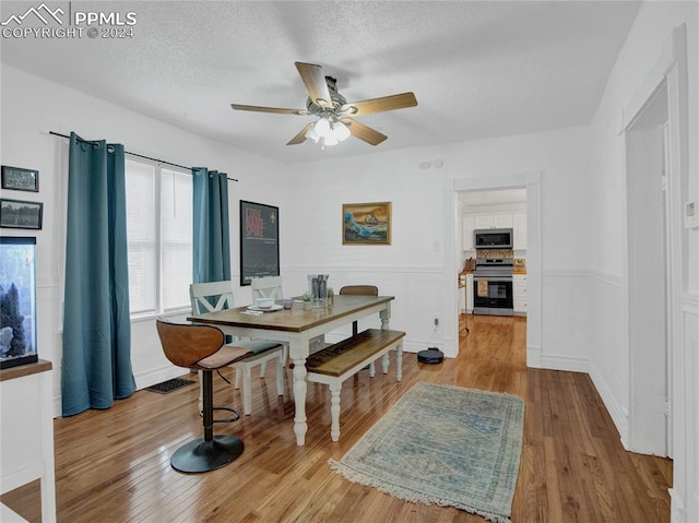 dining room featuring a textured ceiling, light hardwood / wood-style flooring, and ceiling fan