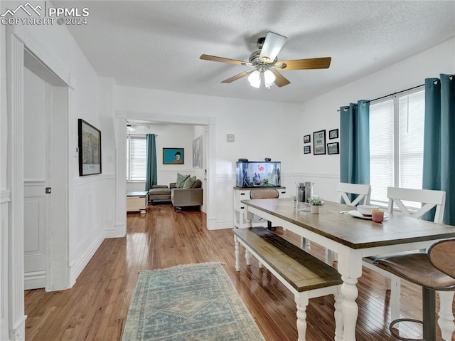 dining room featuring light wood-type flooring, a textured ceiling, and ceiling fan