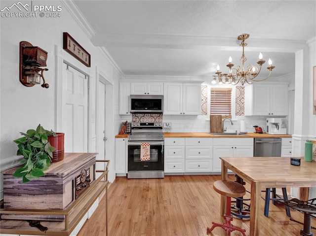 kitchen with light hardwood / wood-style flooring, decorative light fixtures, stainless steel appliances, a notable chandelier, and sink