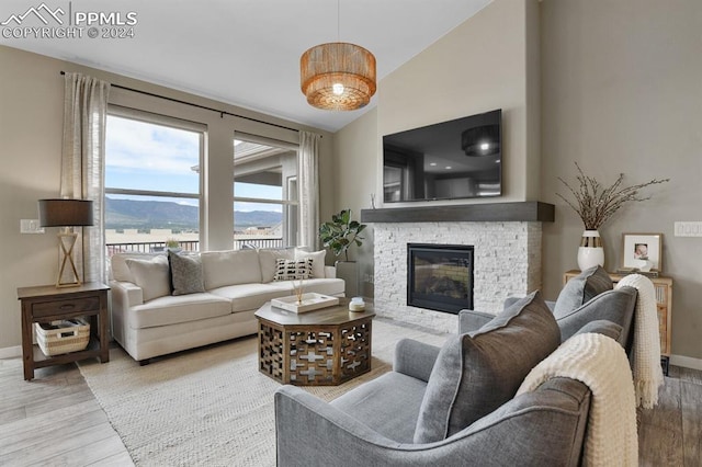 living room with lofted ceiling, a stone fireplace, and wood-type flooring