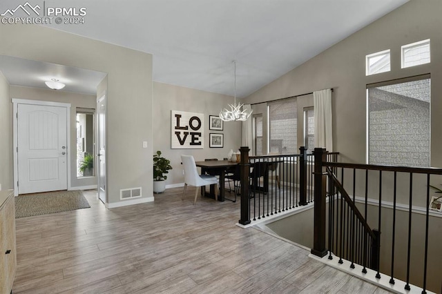 foyer featuring hardwood / wood-style flooring, high vaulted ceiling, and a chandelier