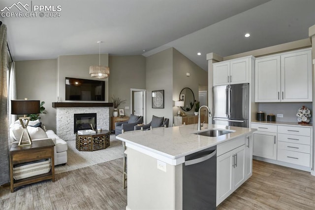 kitchen featuring sink, stainless steel refrigerator, black dishwasher, an island with sink, and white cabinets