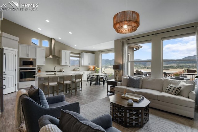 living room featuring high vaulted ceiling, wood-type flooring, a mountain view, and sink